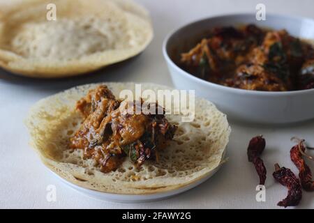 Trichter aus Füchsschwanzmilchetten. Eine experimentelle Version eines beliebten Kerala-Gerichts namens Appam serviert mit Kerala-Chicken-Kerridhuly, das mit zu Hause zubereitet wird Stockfoto