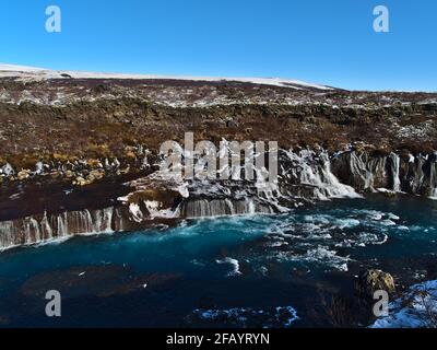 Atemberaubende Aussicht auf die berühmten Hraunfossar-Kaskaden (isländisch: Lavafälle) bei Húsafell im Westen Islands an sonnigen Wintertagen mit tobendem Fluss. Stockfoto