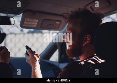 Smiley Rothaariger bärtiger Kerl mit lockigen Haaren lacht in einem Auto Stockfoto