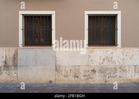 Zwei Vintage-Fenster mit Eisengitter an einer Steinwand. Valencia, Spanien Stockfoto