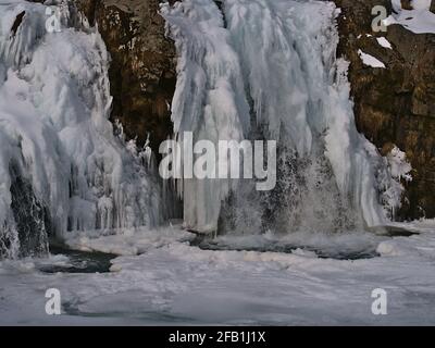 Nahaufnahme des gefrorenen felsigen Kirkjufellsfoss Wasserfalls in der Nähe von Grundarfjörður auf der Halbinsel Snæfellsnes, im Winter im Westen Islands mit Schnee und Eis. Stockfoto