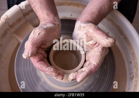 Potter-Rad und Hände des Handwerkers, der einen Krug macht. Draufsicht. Stockfoto