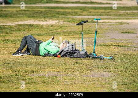 WIMBLEDON LONDON, GROSSBRITANNIEN. 23. April 2021. Eine Frau, die an einem schönen sonnigen Tag auf dem Rasen am Wimbledon Common, London, liegt, während Prognostiker ein wärmeres Wetter vorhersagen, wobei die Temperaturen am Wochenende in London und im Südosten Englands voraussichtlich 19 Grad Celsius erreichen werden. Kredit: amer ghazzal/Alamy Live Nachrichten Stockfoto