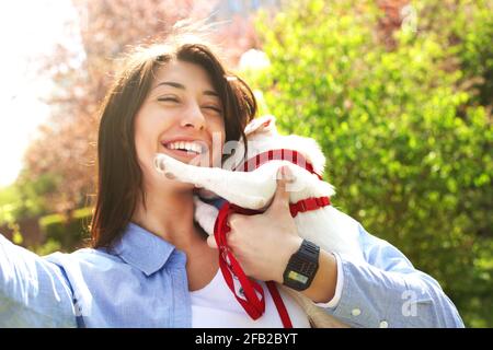 Schöne junge Frau nimmt Selfie mit ihrem niedlichen Jack russell Terrier Welpen auf Picknick im Park, grünes Gras & Laub Hintergrund. Weibliche Besitzerin & klein Stockfoto