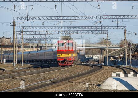 SHARYA, RUSSLAND - 10. APRIL 2021: Die tschechische Elektrolokomotive CHS-4t mit Personenzug fährt vom Bahnhof Sharya der Nordbahn ab Stockfoto