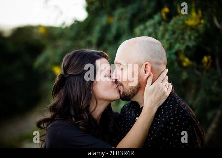 Ehemann und Ehefrau küssen im Garten in San Diego Stockfoto