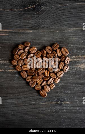 Kaffeebohnen im Herzen bilden sich auf dem schwarzen Hintergrund Stockfoto