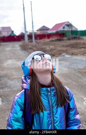 Teenager-Mädchen in verspiegelter Sonnenbrille blickt in den Himmel. Wellness-Konzept Stockfoto