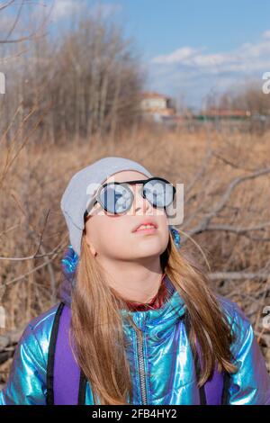 Teenager-Mädchen in verspiegelter Sonnenbrille blickt in den Himmel. Wellness-Konzept Stockfoto