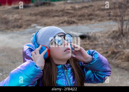 Teenager-Mädchen in verspiegelter Sonnenbrille blickt in den Himmel. Wellness-Konzept Stockfoto