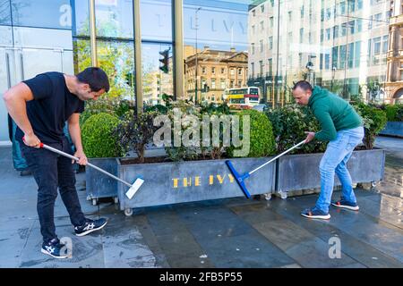 Edinburgh, Schottland, Großbritannien. 23. April 2021. Bars und Restaurants bereiten sich darauf vor, am Montag wieder zu öffnen, wenn die Sperre um 19 Uhr entspannt ist und Geschäfte und Geschäfte wieder handeln dürfen. Das Personal ist mit der Reinigung und Einrichtung von Sitzbereichen im Freien beschäftigt, damit die Gäste essen und trinken können. Bild: Das Personal im Ivy Restaurant putzt und schrubbt den Sitzbereich im Freien. Iain Masterton/Alamy Live News Stockfoto