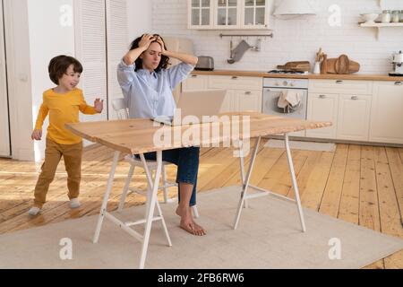 Laute Sohn stören beschäftigt Mutter Arbeit Remote von Home Office Während der covid-19-Quarantänesperre Stockfoto