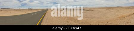 Straße in der Kalahari-Wüste, Namibia, Panorama mit bewölktem und blauem Hintergrund Stockfoto