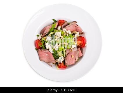 Warmer Roastbeef-Salat mit Ziegenkäse und Tomaten. Isoliert auf weißem Hintergrund. Stockfoto