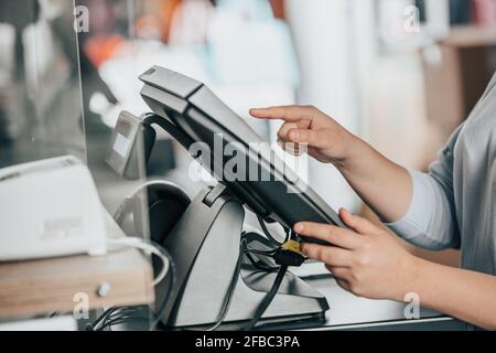 Junge Frau Hand eine Zahlung für ein paar Kleidung Durch Touchscreen Treasury in riesigen Einkaufszentrum Stockfoto