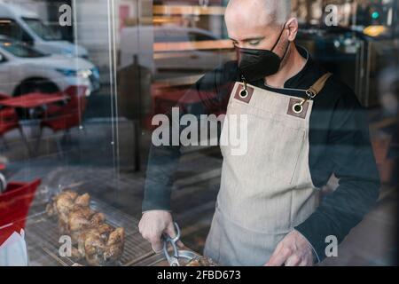 Reifer männlicher Restaurantbesitzer, der im Handel gebratenes Hühnerfleisch schneidet Küche Stockfoto