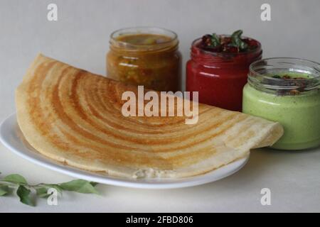 Knuspriger Pfannkuchen aus Reis und Linsen. Serviert mit würzigen Kokosnussgewürzen aus Rote Beete, Koriander-Kokoswürzen und Sambar Stockfoto