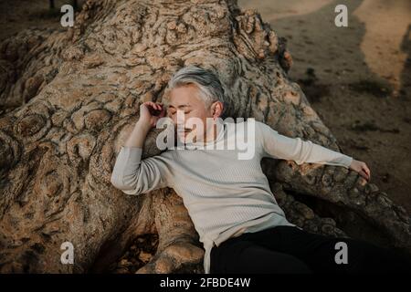 Reifer Mann, der im Garten inmitten von Pflanzen steht und aufschaut Stockfoto