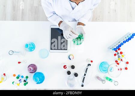 Forscherin testet Flüssigkeit in Kolben auf dem Tisch im Labor Stockfoto