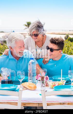 Lächelnder Junge mit fröhlichen Großeltern, die am Wochenende zu Mittag essen Stockfoto