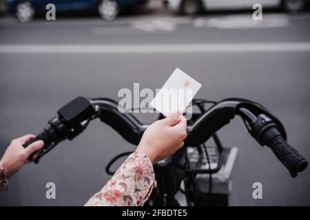 Frau mit Kreditkarte, um Fahrrad in der Stadt zu mieten Stockfoto