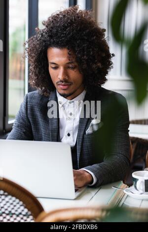 Junge freiberufliche Mitarbeiterin, die im Café an einem Laptop arbeitet Stockfoto
