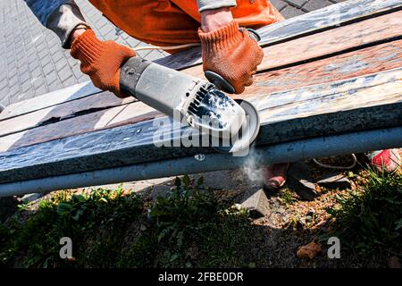 Holz schleifen, Farbe einer alten Bank reinigen. Vorbereitung für das Lackieren. Die städtischen Dienste bereiten die Stadt auf die Sommersaison vor. Stockfoto