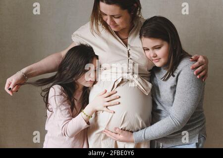 Töchter umarmen Schwangeren Mutter zu Hause stehen Stockfoto