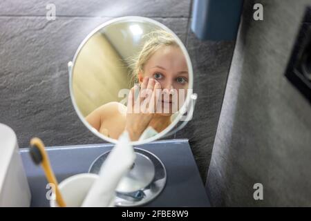Spiegelung der Frau Reinigung Gesicht mit Wattepad im Badezimmer Stockfoto