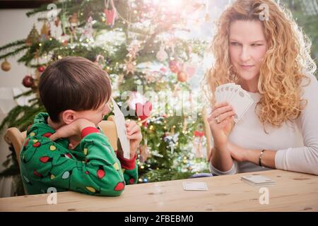 Mutter und Sohn spielen zu Weihnachten Karten am Tisch Stockfoto