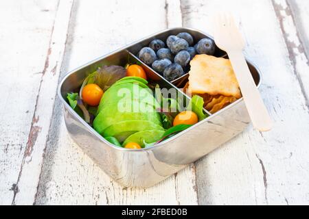 Lunchbox mit Salat, Avocado und gelben Tomaten, Crackern und Heidelbeeren Stockfoto