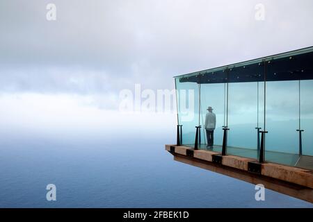 Mann, der auf dem Skywalk vor dem Himmel steht Stockfoto