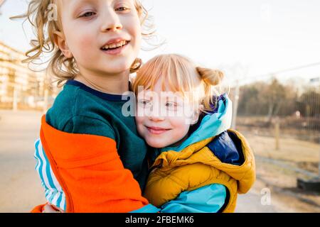 Lächelnder Junge umarmt niedliche Schwester Stockfoto