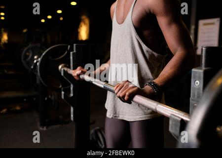 Junger Mann, der sich beim Training im Fitnessstudio auf das Heben der Langhantel vorbereitet Stockfoto