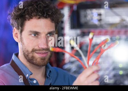 Männlicher IT-Techniker, der sich die Patchkabel in den Daten ansieht Zentrieren Stockfoto