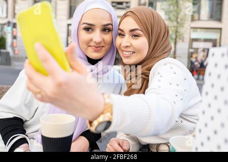 Junge Frau, die mit einer Freundin Selfie über ein Smartphone nimmt In der Stadt Stockfoto