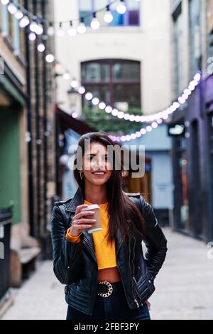 Schöne Frau mit Einweg-Kaffeetasse auf der Straße in stehen Stadt Stockfoto