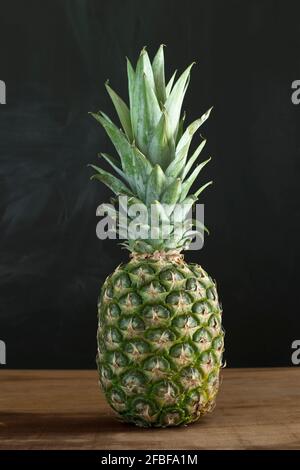 Stillleben mit Ananas vor dunkler Wand Stockfoto