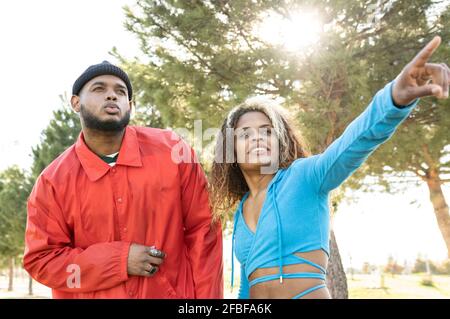 Männliche und weibliche Freunde blicken weg, während sie im Park stehen Stockfoto
