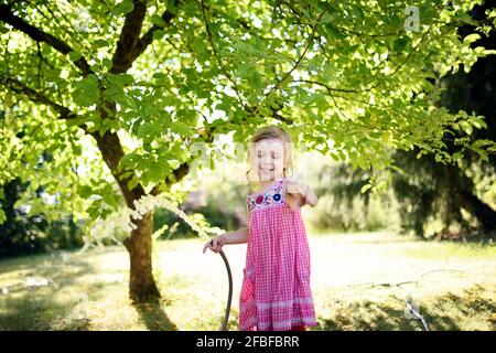 Glückliches Mädchen gestikuliert, während die Wasserpfeife im Garten gehalten wird Stockfoto