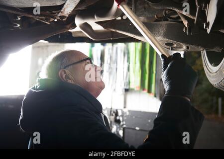 Männlicher Automechaniker, der Auto im Laden repariert Stockfoto