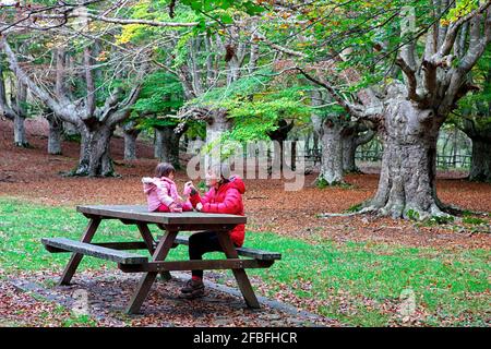 Mutter sitzt mit Tochter auf der Bank im Gorbea Naturpark Stockfoto