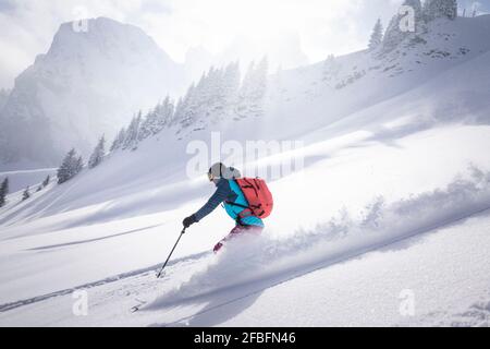 Frau mit mittlerem Erwachsenen, die an sonnigen Tagen auf einem schneebedeckten Berg Ski fährt Stockfoto