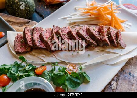 Kalbsfleisch serviert mit Rettich und Karotten auf dem Teller Restaurant Stockfoto