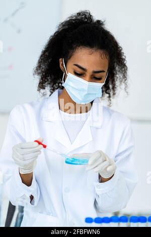 Junge Forscherin testet Flüssigkeit im Chemielabor während des COVID-19 Stockfoto