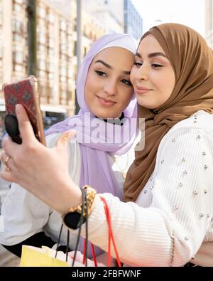 Arabische Freundinnen, die beim Einkaufen Selfie über das Smartphone machen Stockfoto