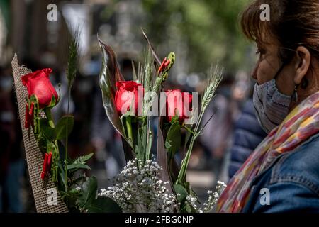 Barcelona, Spanien. April 2021. Eine Frau wird vor einem der traditionellen Blumenläden auf den Ramblas in Barcelona beim Kauf roter Rosen gesehen.Trotz der Kapazitätskontrolle und der Distanzierungsmaßnahmen aufgrund der Covid-Pandemie gewinnt Barcelona erfolgreich das Fest von Sant Jordi, der schutzpatronin von Katalonien, Mit dem traditionellen Tag des Verkaufs von Büchern und Rosen. (Foto von Paco Freire/SOPA Images/Sipa USA) Quelle: SIPA USA/Alamy Live News Stockfoto