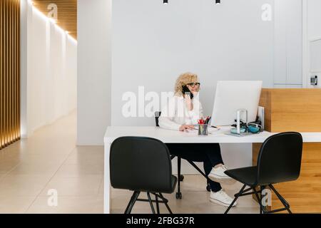 Reifer Rezeptionist, der im Zahnarztbüro über das Mobiltelefon spricht Stockfoto