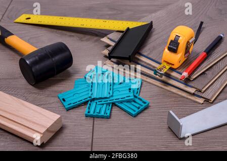 Planken von Laminatboden und Ausrüstung oder Werkzeuge, um sie zu installieren, Hammer, Brecheisen, Distanzstücke, Hammer und Meter. Selektiver Fokus. Stockfoto