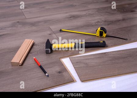 Ausrüstung oder Werkzeuge zum Einbau von Laminatboden, Hammer, Hammer, Bleistift und Messgerät. Selektiver Fokus. Stockfoto